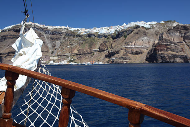 Old boat off the coast of Santorini looking at island stock photo