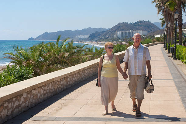 senior couple walking on holiday or are they expatriates senior couple stroll next to beach on holidayPlease see some similar pictures from my portfolio: expatriate photos stock pictures, royalty-free photos & images