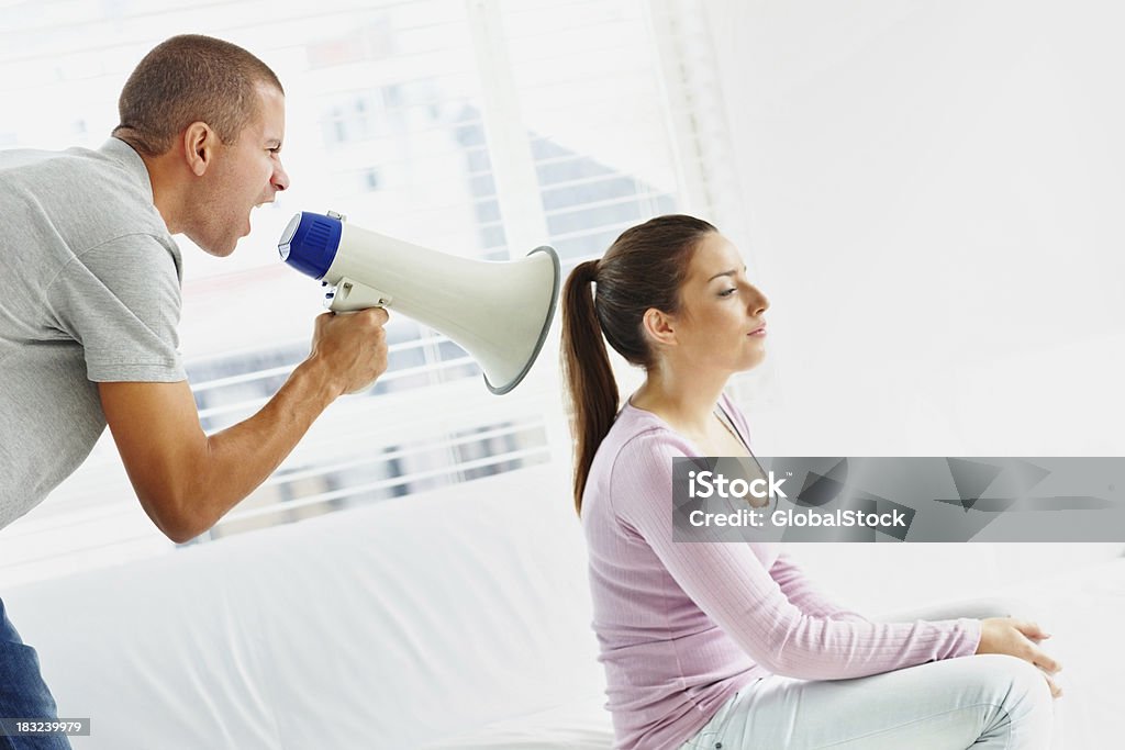 Husband using a megaphone to scream at his wife Relation issues - Husband using a megaphone to yell at wife 20-29 Years Stock Photo