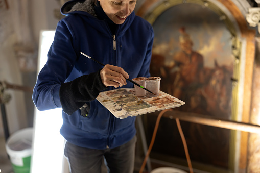 Female Painter Expertly Prepares Restoration Colors for Gothic Fresco in Historic Church. Skilled and Confident Adult Female Artisan at Work