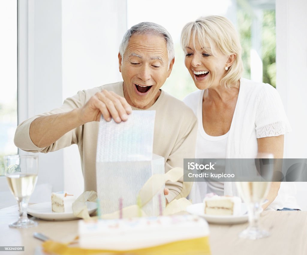 Überrascht alter Mann mit Frau öffnen ein Geschenk auf Geburtstag - Lizenzfrei Alter Erwachsener Stock-Foto