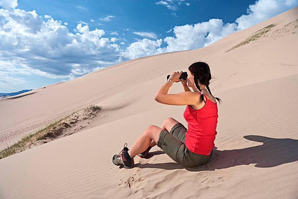 istock Young woman is looking through a binoculars on the desert 183240328