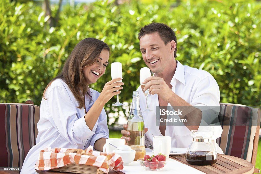 Happy couple celebrating Young couple enjoying romantic breakfast with glass of champagne and strawberries on the terrace. 20-29 Years Stock Photo