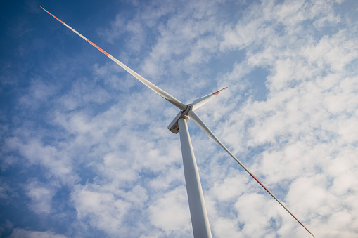 Bottom Down Point Of View Of Wild Turbines Against Blue Sky generating clean carbon neutral energy.