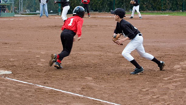 Play Action First baseman and runner in action in a little league baseball game.  Motion blur.See my other little league baseball images: baseball helmet stock pictures, royalty-free photos & images