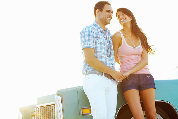 istock Loving young couple leaning against convertible car, smiling 183241298