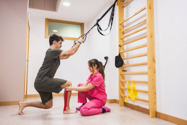 A physical therapist works with a patient on their leg muscles in a clinical setting. stock photo