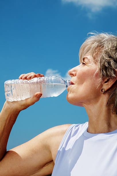 Elderly female drinking water after workout Portrait of a elderly female drinking water after workout - Outddor water athlete competitive sport vertical stock pictures, royalty-free photos & images