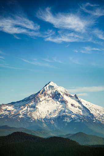 A scenic view of Mt. Hood, and the surrounding hills, a gorgeous cloudscape and blue sky overhead.  One of the many beautiful mountains in the Pacific Northwest.  Vertical with copy space.