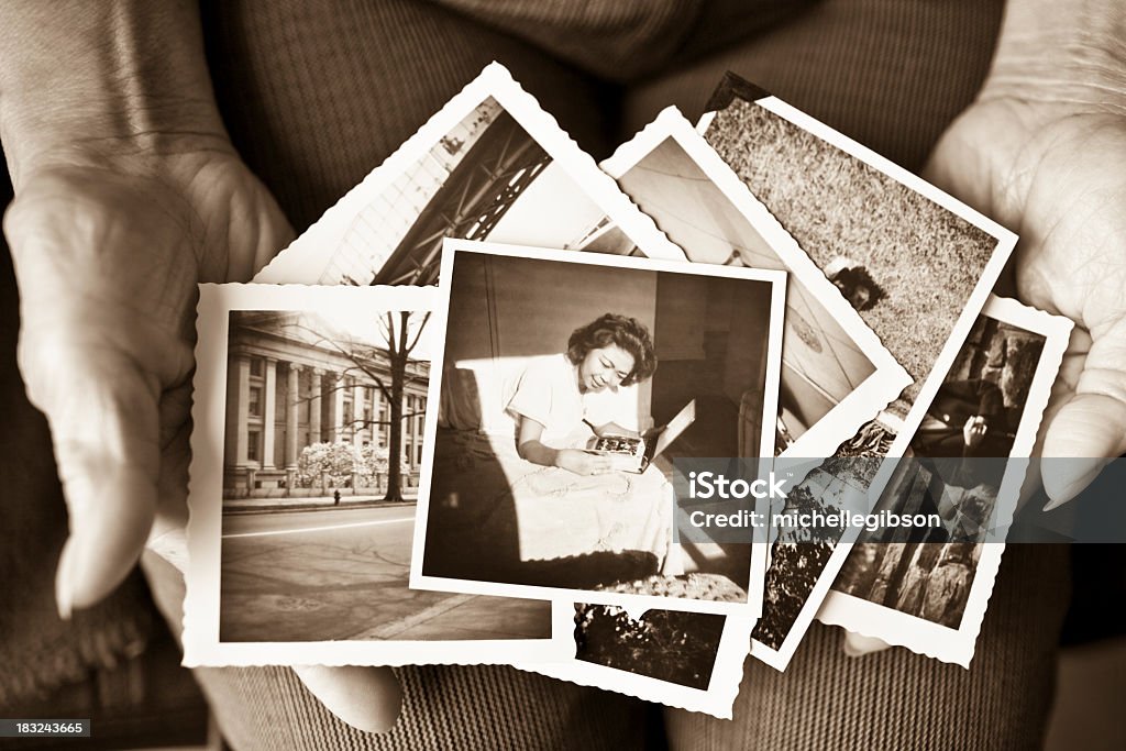 Elderly woman holding a collection of old photographs Toned image of an elderly, senior woman holding old vintage photographs of herself and of other places in her hands, showing her sentimental memories, past, and places travelled.  Only her hands are shown in the image Photograph Stock Photo
