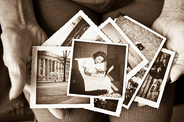 Elderly woman holding a collection of old photographs Toned image of an elderly, senior woman holding old vintage photographs of herself and of other places in her hands, showing her sentimental memories, past, and places travelled.  Only her hands are shown in the image the past stock pictures, royalty-free photos & images