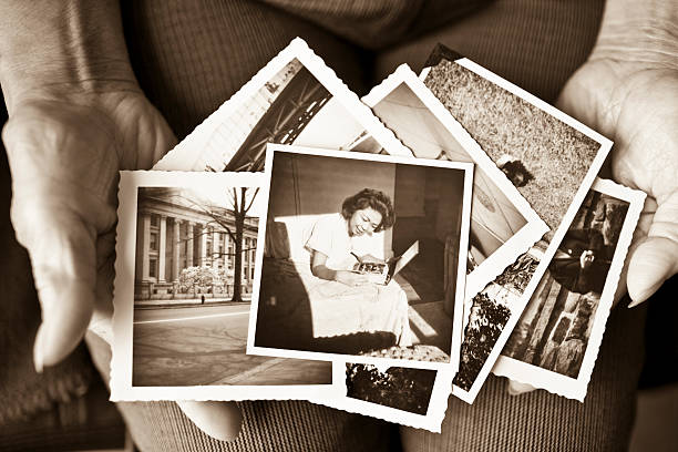 Elderly woman holding a collection of old photographs Toned image of an elderly, senior woman holding old vintage photographs of herself and of other places in her hands, showing her sentimental memories, past, and places travelled.  Only her hands are shown in the image macro photos stock pictures, royalty-free photos & images