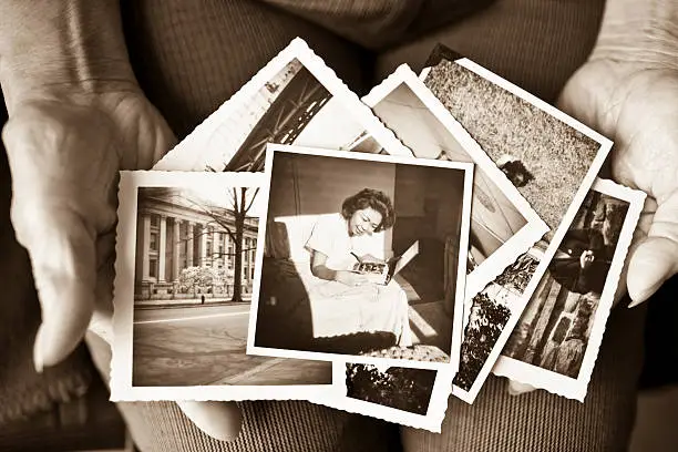 Photo of Elderly woman holding a collection of old photographs