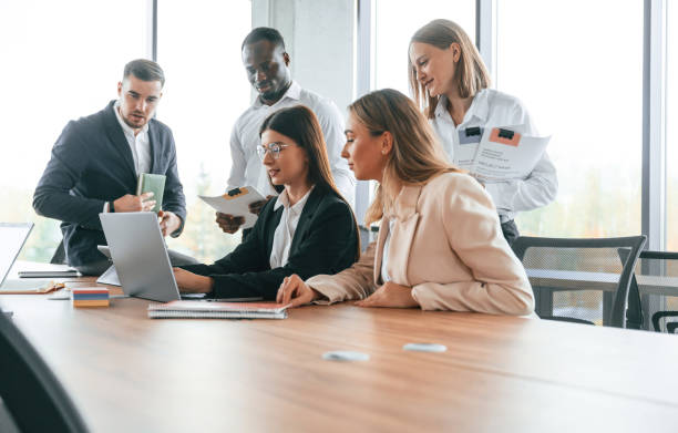 istock Using laptop that is on the table. Group of office workers are together indoors 1832439168