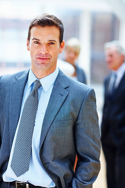 istock Confident middle aged executive with blur team in background 183244309