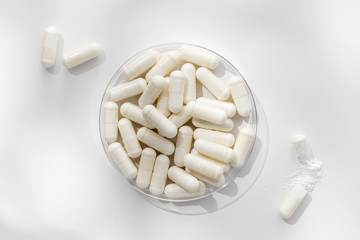 White medicinal capsules in a Petri dish, vitamins and supplements. The concept of medicine, medicines.