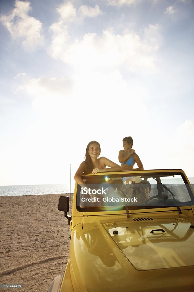 笑顔の女性が彼女のご友人とご一緒にビーチでのジープ - オフロード車のロイヤリティフリーストックフォト