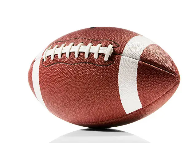 A brown and white american football isolated on a white background with a clipping path. The ball casts a soft shadow on the white background. The leather forms a pitted texture and the ball has white lines painted around it with white laces across the middle.