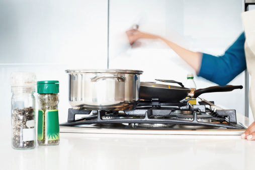 Closeup of a kitchen hob with utensils and blurred motion of female hand stirring