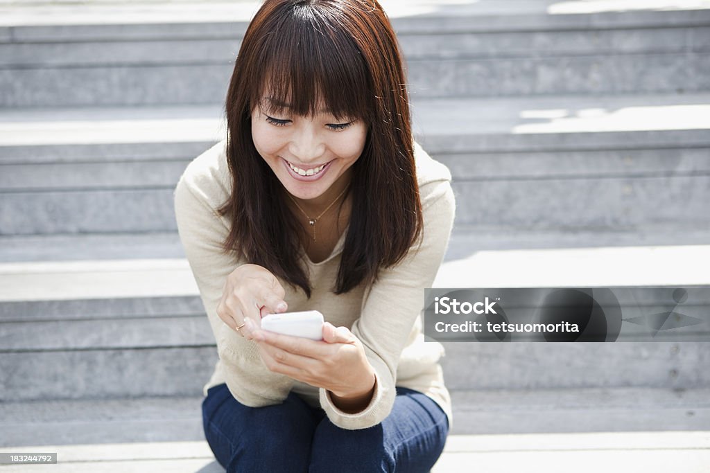 Young woman uses the smartphone. She sits in the stairs.Other image from this session: Adult Stock Photo