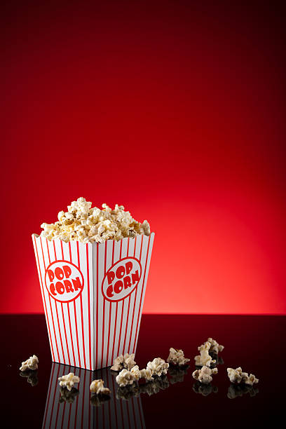 istock Box of popcorn on reflective surface and red background 183245006