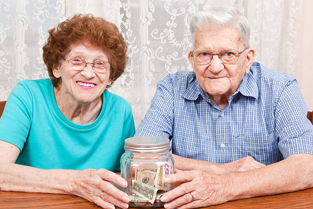 A mid-80's couple smiling together and holding a jar with money in it.