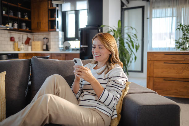 istock Cheerful beautiful woman relaxing at home and using smart phone 1832467372