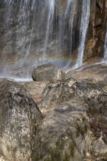 istock a rainbow is shining over some water near rocks and trees 1832468951