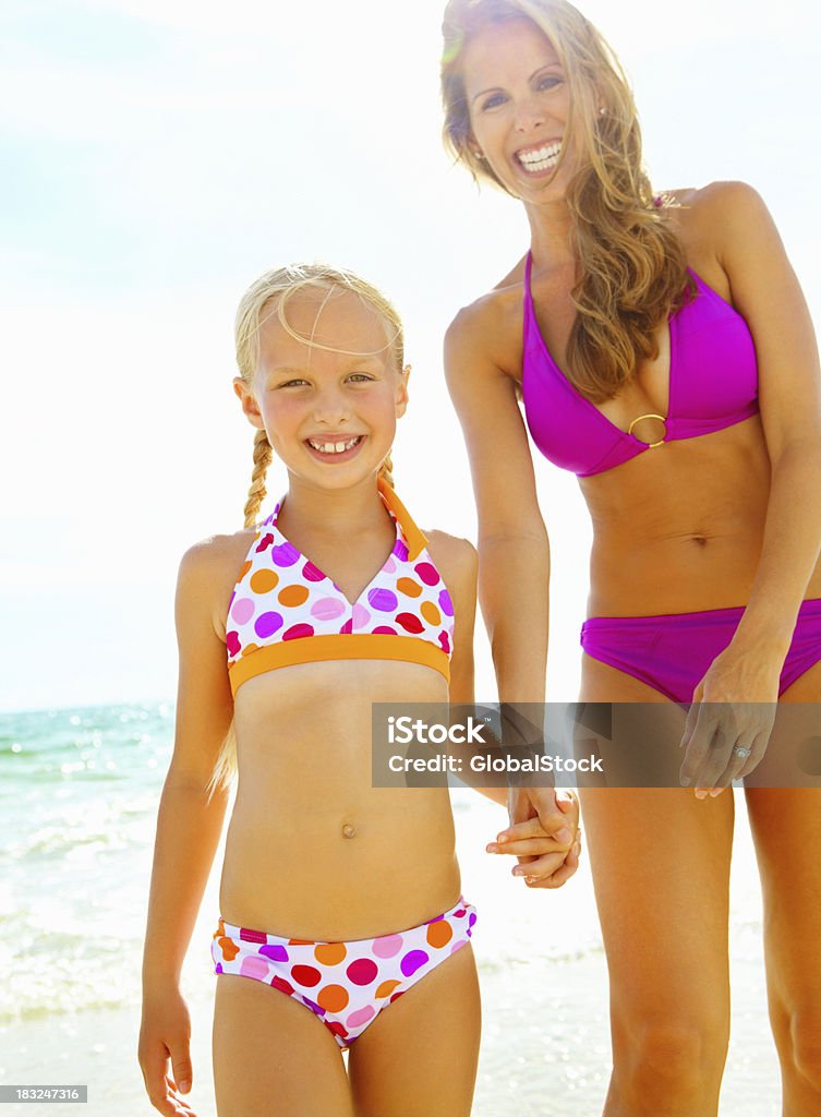Madre e hija holding hands on the beach - Foto de stock de Biquini libre de derechos