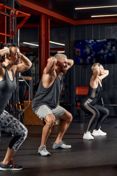 istock Young and active people on group sports training together do warming up and doing exercise for arm stretch. People train in spacious bright gym. Concept of sport and healthy lifestyle 1832474905