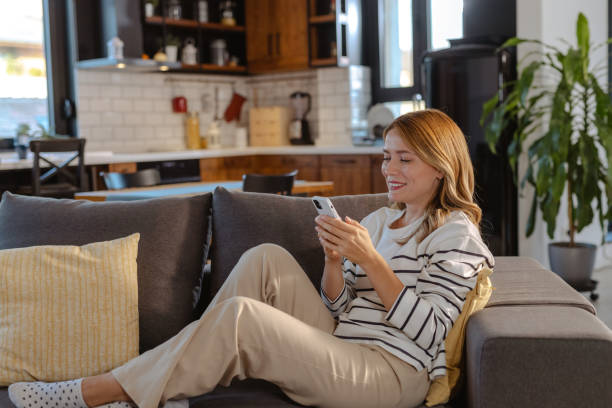 istock Cheerful beautiful woman relaxing at home and using smart phone 1832475431