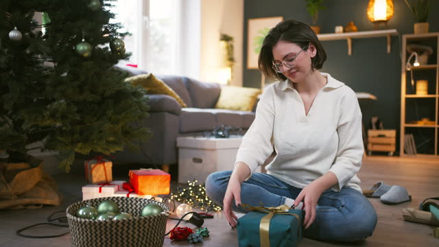 Portrait of an young woman with presents near the Christmas tree