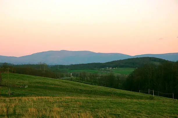 Rolling hills and mountain range in background during sunset.