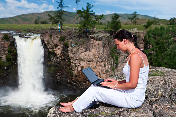 giovane donna con computer portatile sulla roccia - stream river water spring foto e immagini stock