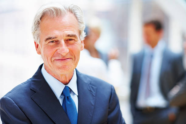istock Happy mature business man with team in blur background 183248631