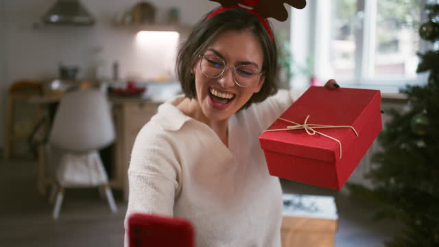 Excited woman showing off her Christmas tree and presents during a video call