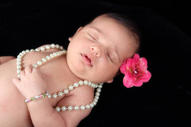 Sleeping Little One Beautiful little 16 day old girl sleeping peacefully wearing pearls and a flower in her hair. Click on image below to view more baby pictures in my Babies lightbox. baby bracelet stock pictures, royalty-free photos & images