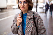 Fashionable young Caucasian woman in a coat, on the street during cold day