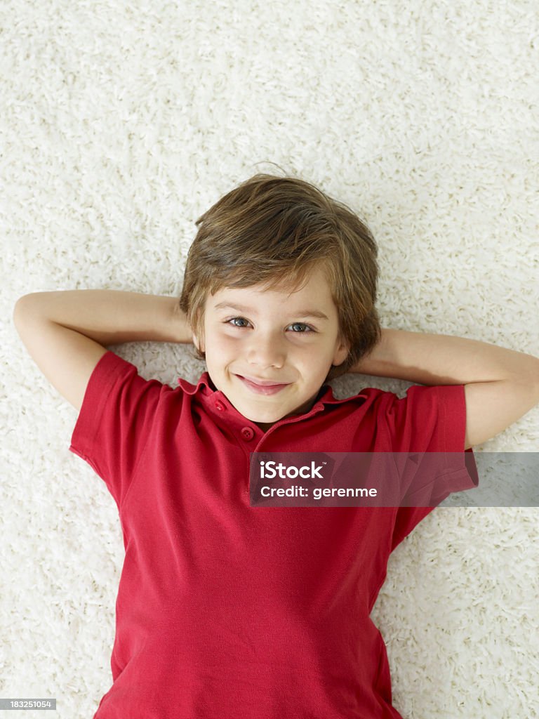 Niño atractivo sonriendo en la alfombra - Foto de stock de Acostado libre de derechos