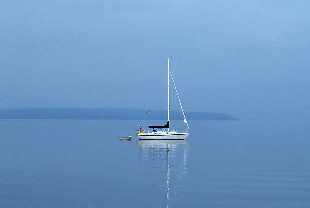 lone sailboat in morning fog stock photo