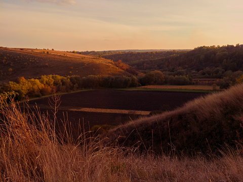 Plowed fields in a valley between hills at sunset. Autumn agronomic landscape.