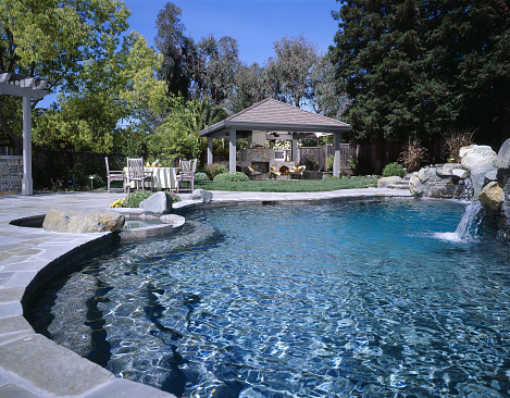 beautiful backyard swimming pool with outdoor patio furniture and gazebbo