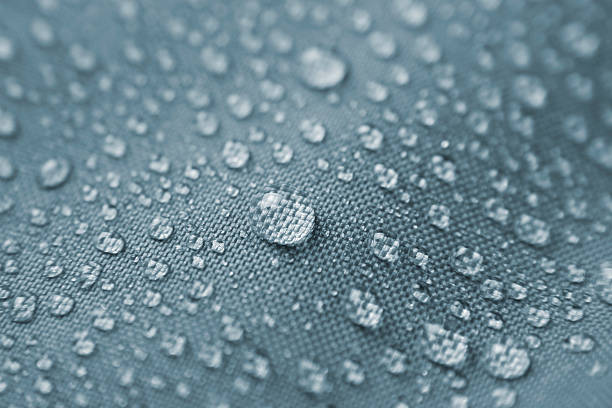 Waterproof textile II Macro shot of rain drops pearling on waterproof nylon jacket. Short DOF. Zoom in on the largest droplet to appreciate the details. polyester photos stock pictures, royalty-free photos & images