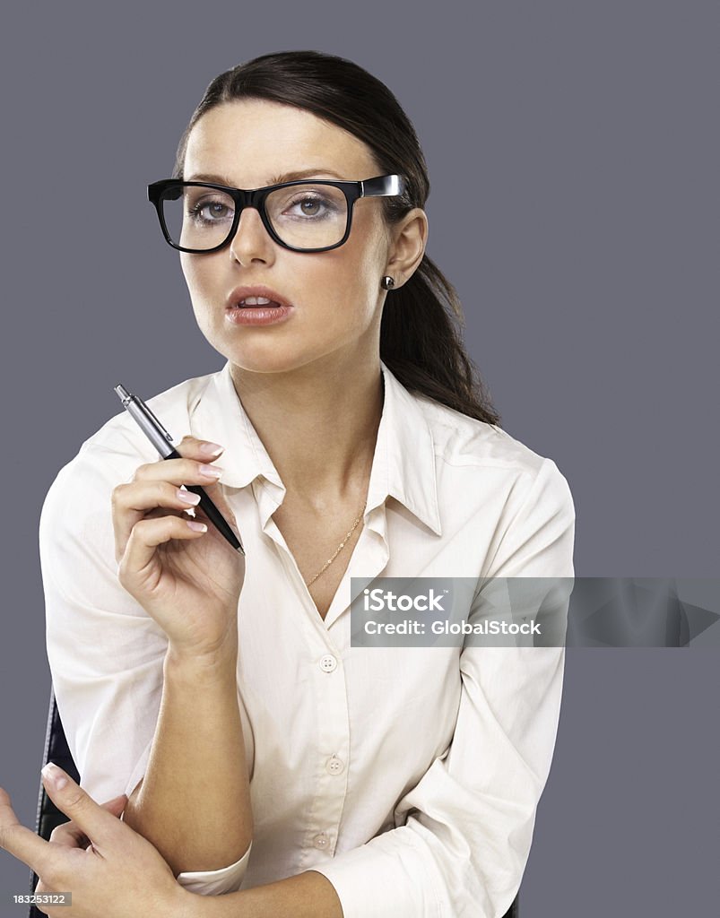 Mujer de negocios joven sosteniendo pen contra el fondo gris - Foto de stock de 20 a 29 años libre de derechos