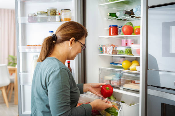 istock Woman takes raw fresh vegetables from fridge 1832542167