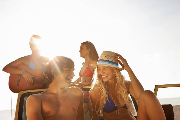 istock Couple sitting on a car with friends in background 183254384