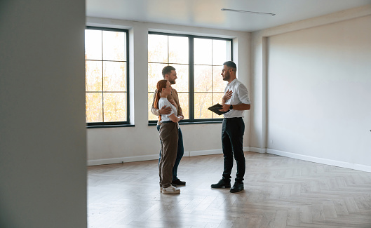 Empty room. real estate agent shows an apartment to a young couple.