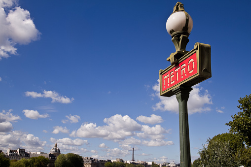 Sign for the metropolitan subway in Paris, France with the Eiffel tower in the background