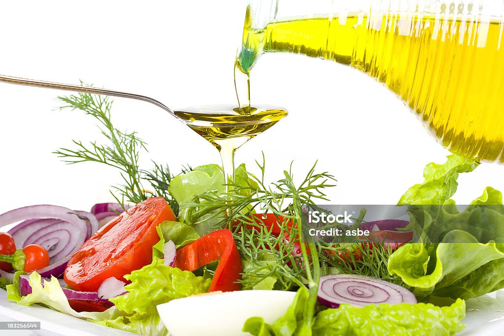 Golden Olive Oil and Vegetable Salad Pouring olive oil into spoon above fresh salad Appetizer Stock Photo