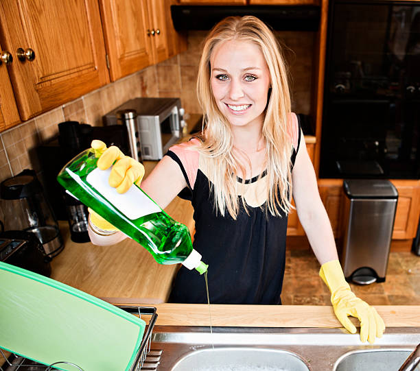 Pretty blonde smilingly pours dishwashing detergent in domestic kitchen "Beautiful young blonde woman gets ready to do the dishes, squeezing out liquid detergent with a smile. Shot with Canon EOS 1Ds Mark III." pedal bin stock pictures, royalty-free photos & images